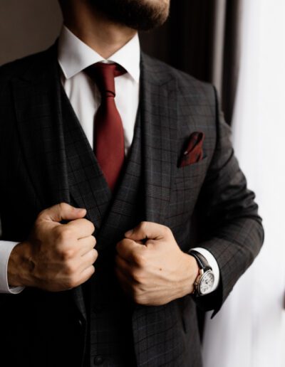 Bearded man in stylish tuxedo and red tie, strong man's hands