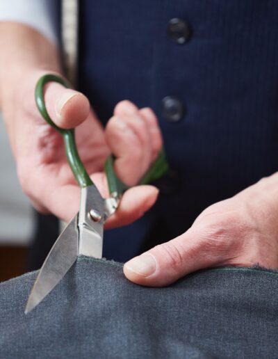 Hands of tailor with scissors cutting fabric